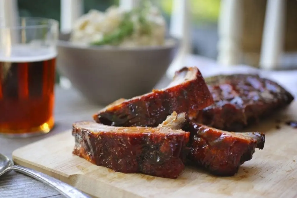 Cooked baby back ribs on a wooden board