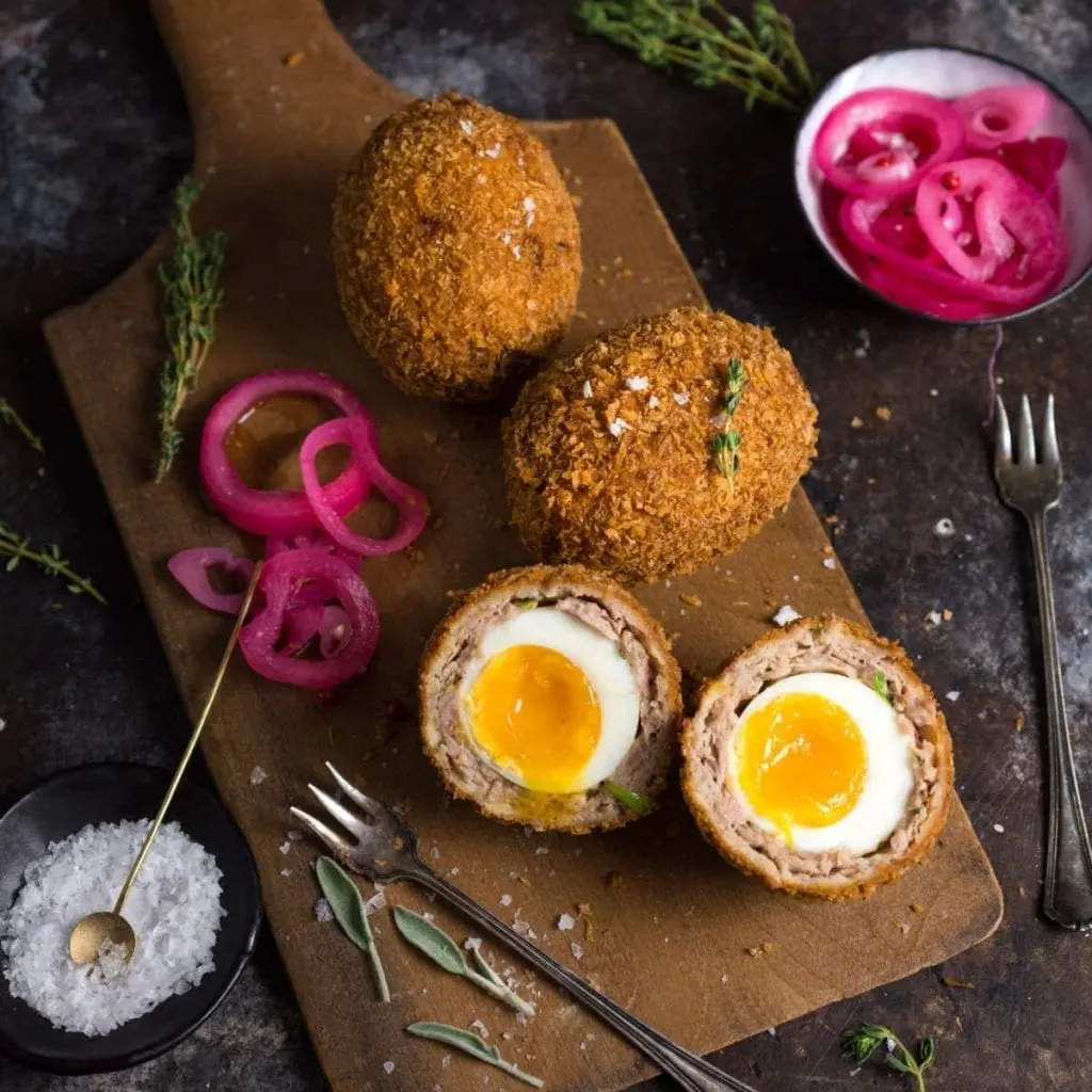 A platter of homemade Scotch Eggs, sliced to reveal the runny yolk