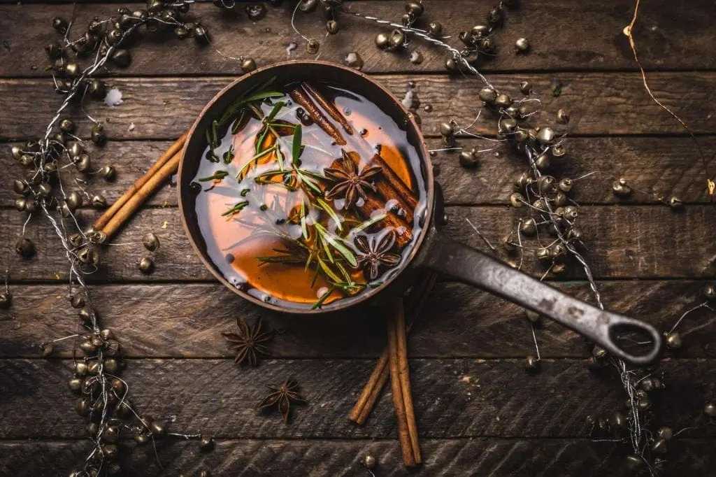 A saucepan of spiced syrup with scattered spices