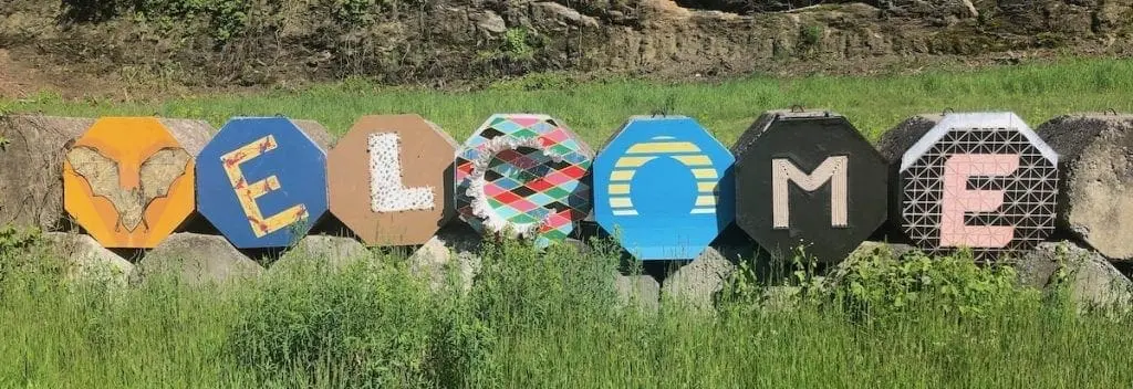The word WELCOME spelled in artwork along a grassy verge