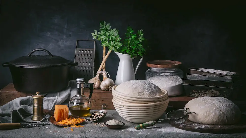 A Dutch oven with two proofing loaves of bread in baskets