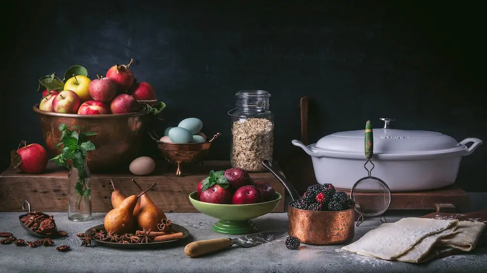 Fruit in bowls next to a bowl of oats and a low Dutch oven