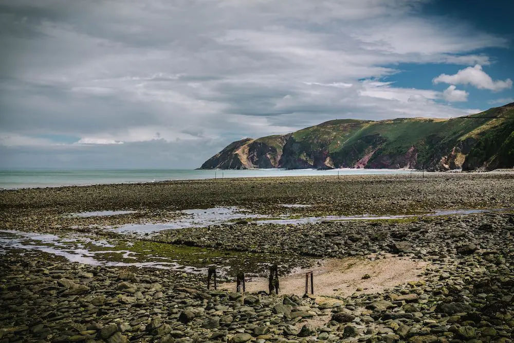 A rocky beach at low tide with cliffs in the background