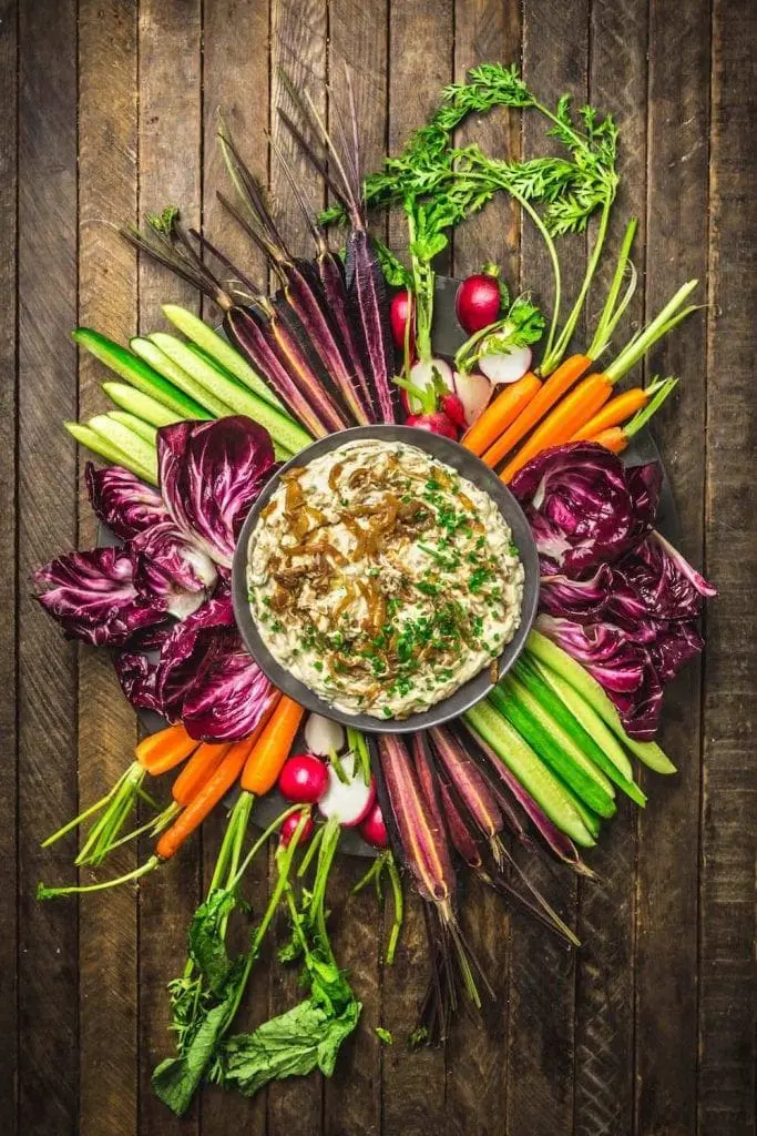 A dip surrounded by colorful cut veggies