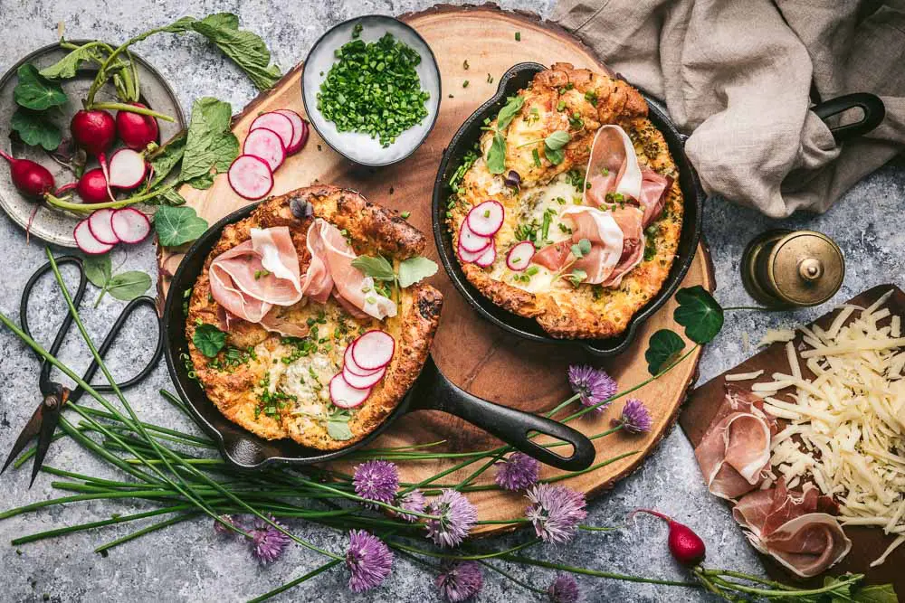Two Dutch Babies in cast iron pans with radishes on top