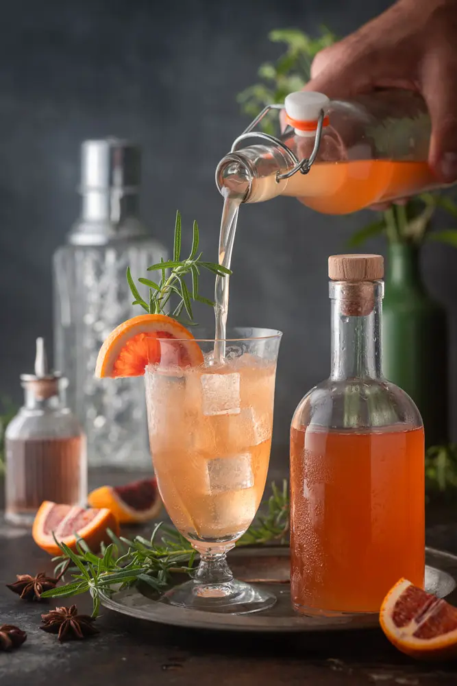 Pouring homemade tonic into a tumbler of ice