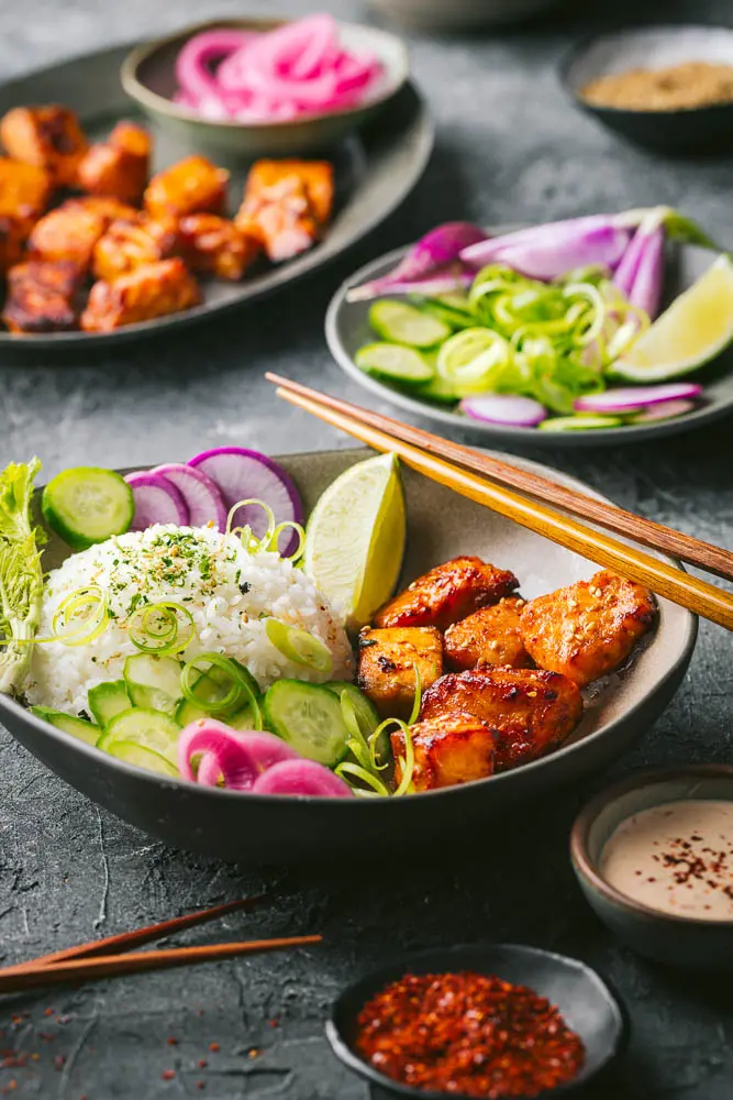 Bowls of the salmon pieces with colorful veggies and chopsticks