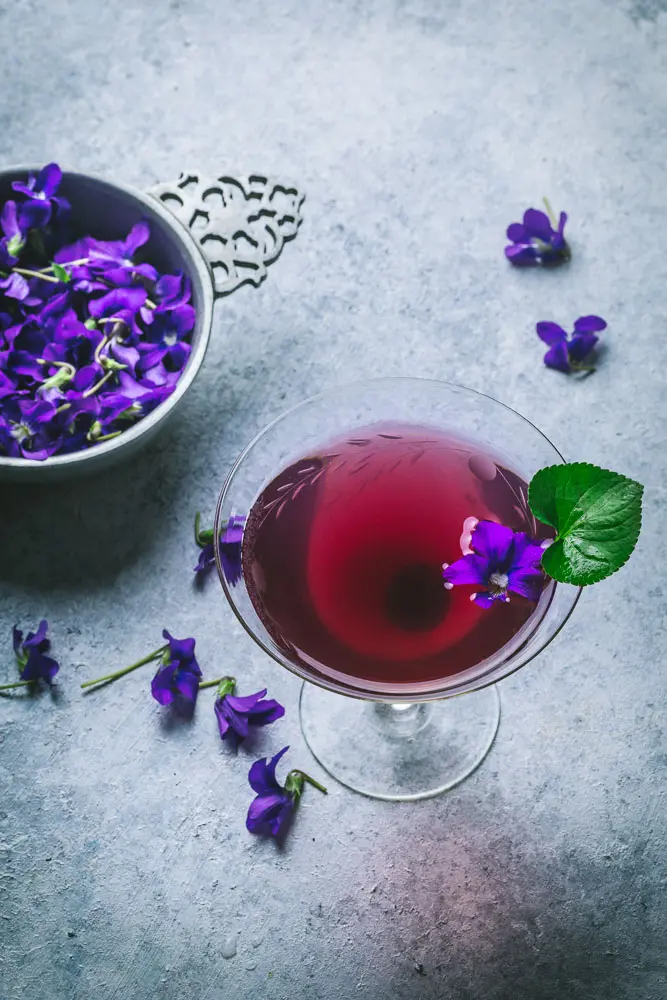 Pretty Cocktail with edible flowers on grey background