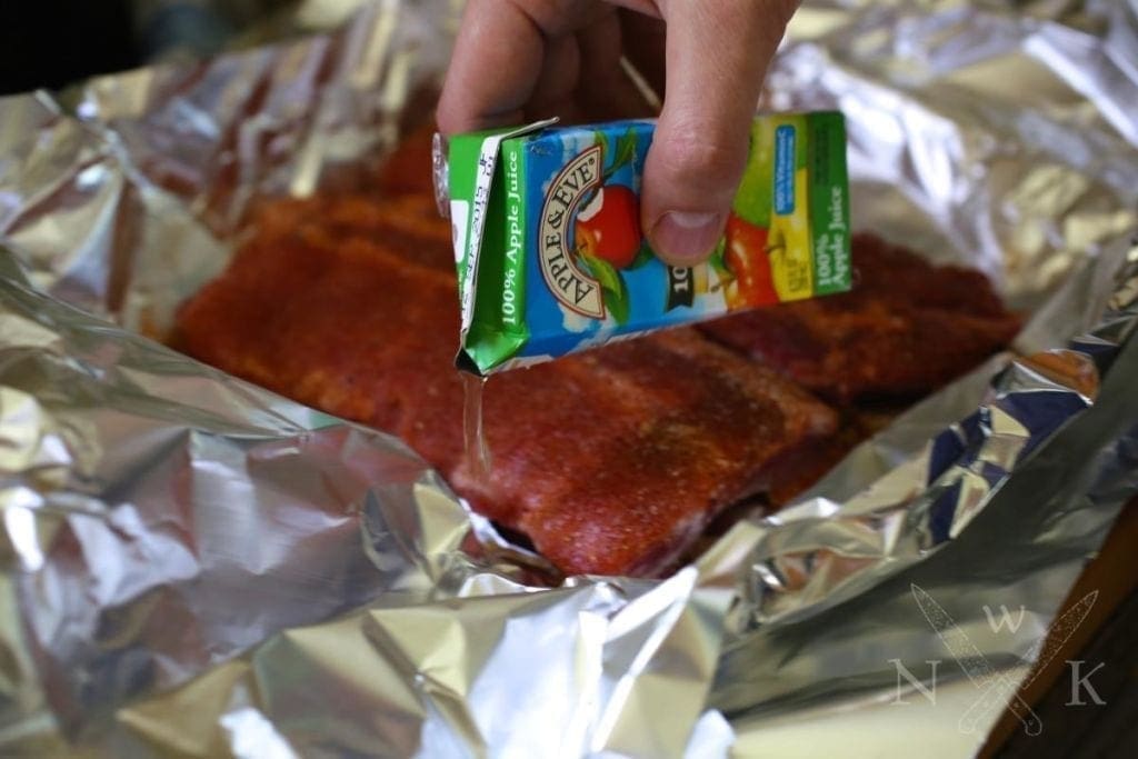 Adding apple juice to a foiled package of ribs