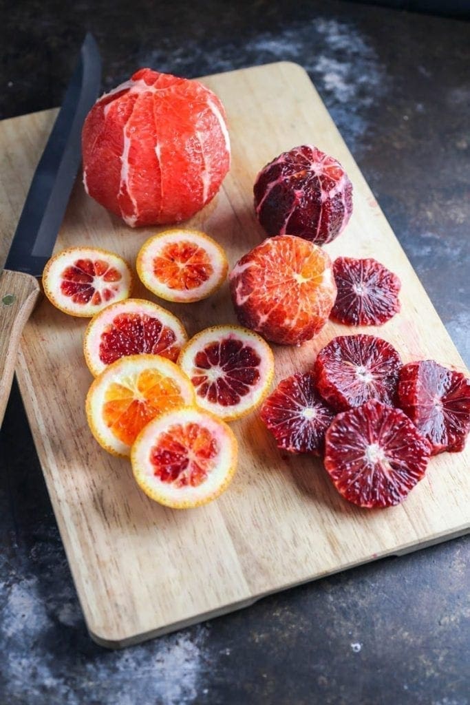A pile of sliced blood oranges on a cutting board