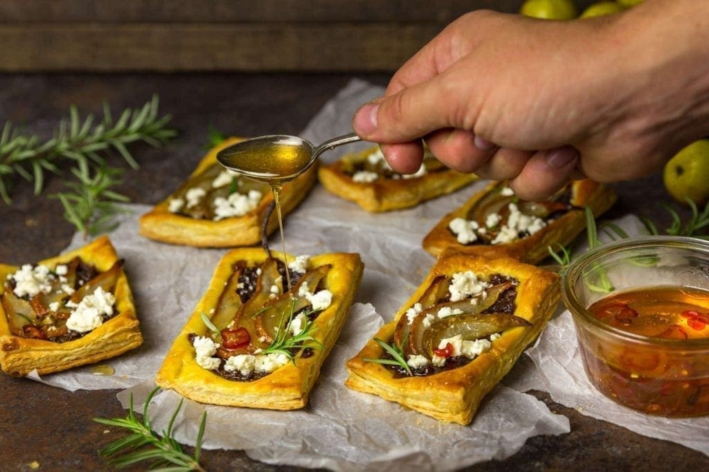 Puff Pastry Tartlets with Roasted Pear, Caramelized Red Onions, Goat Cheese and Spicy Honey Drizzle
