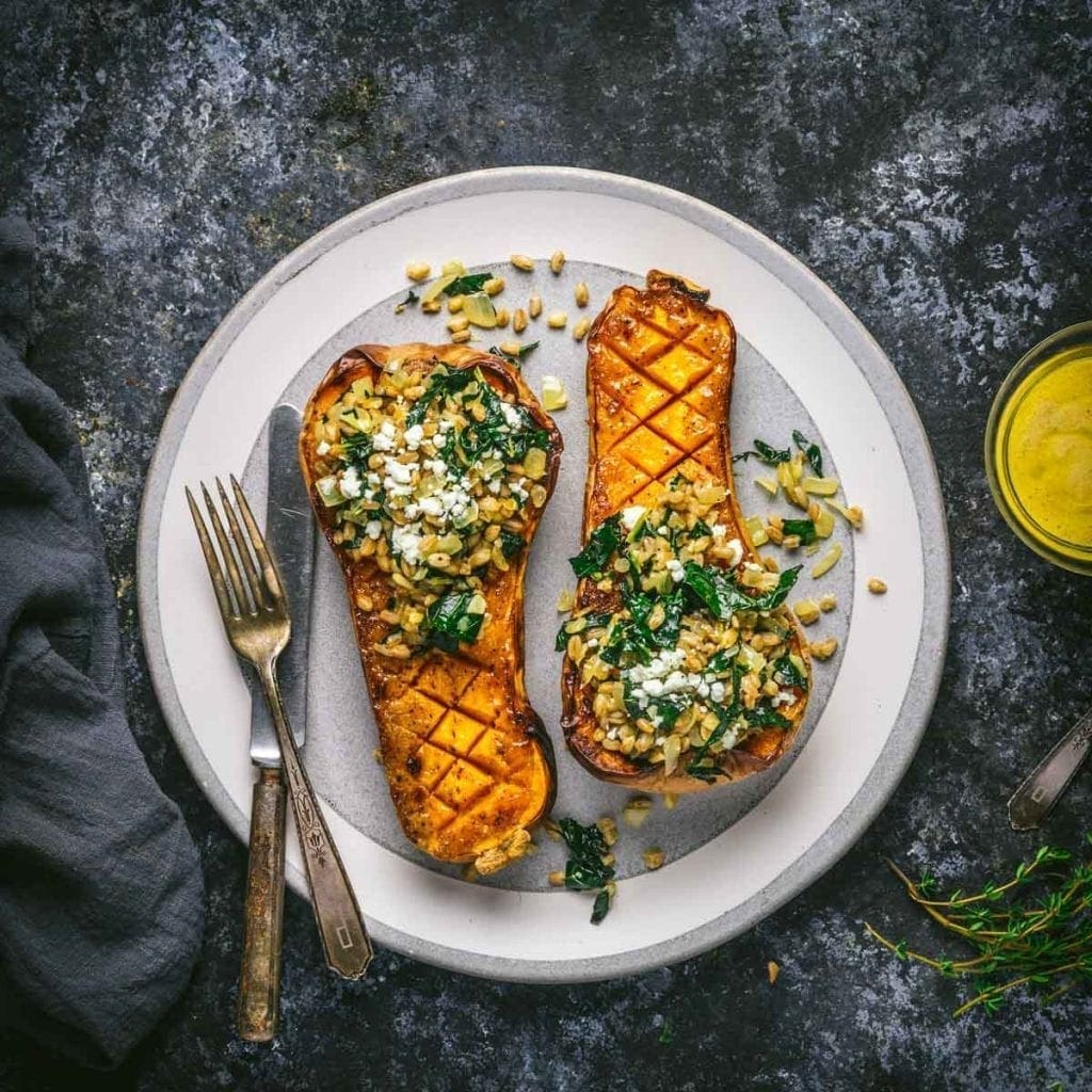 Butternut squash halves stuffed with greens and grains on a plate
