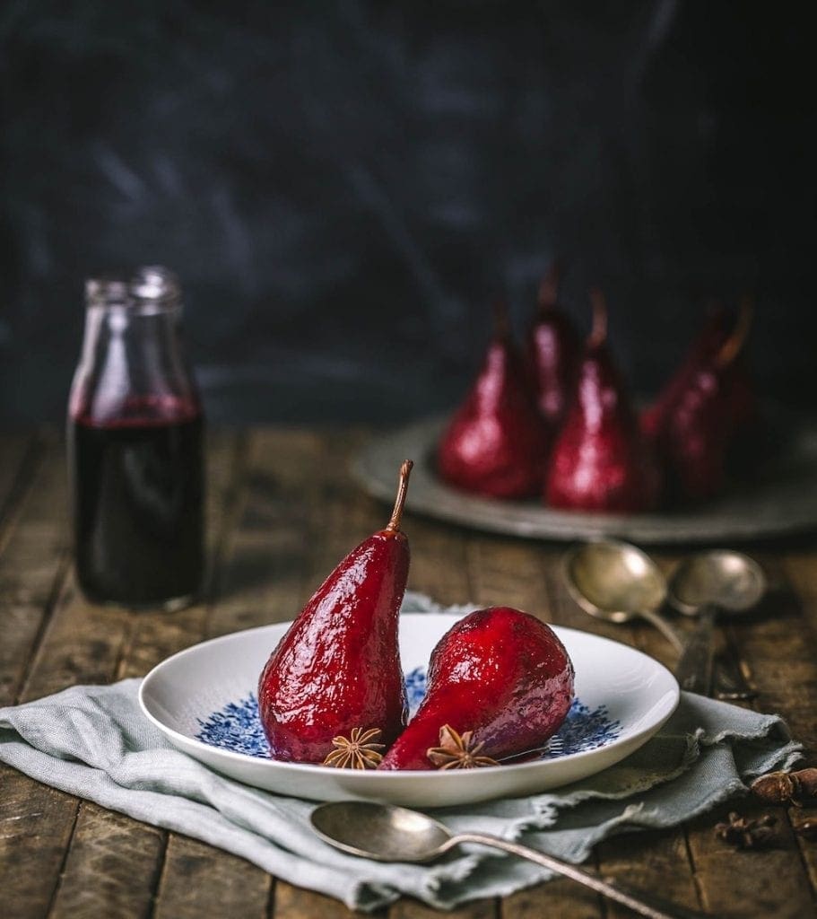 Red poached pears arranged on a plate