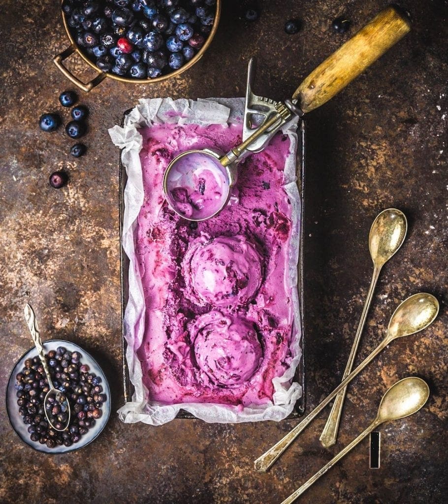 A baking dish of pink ice cream with a scoop sitting in it