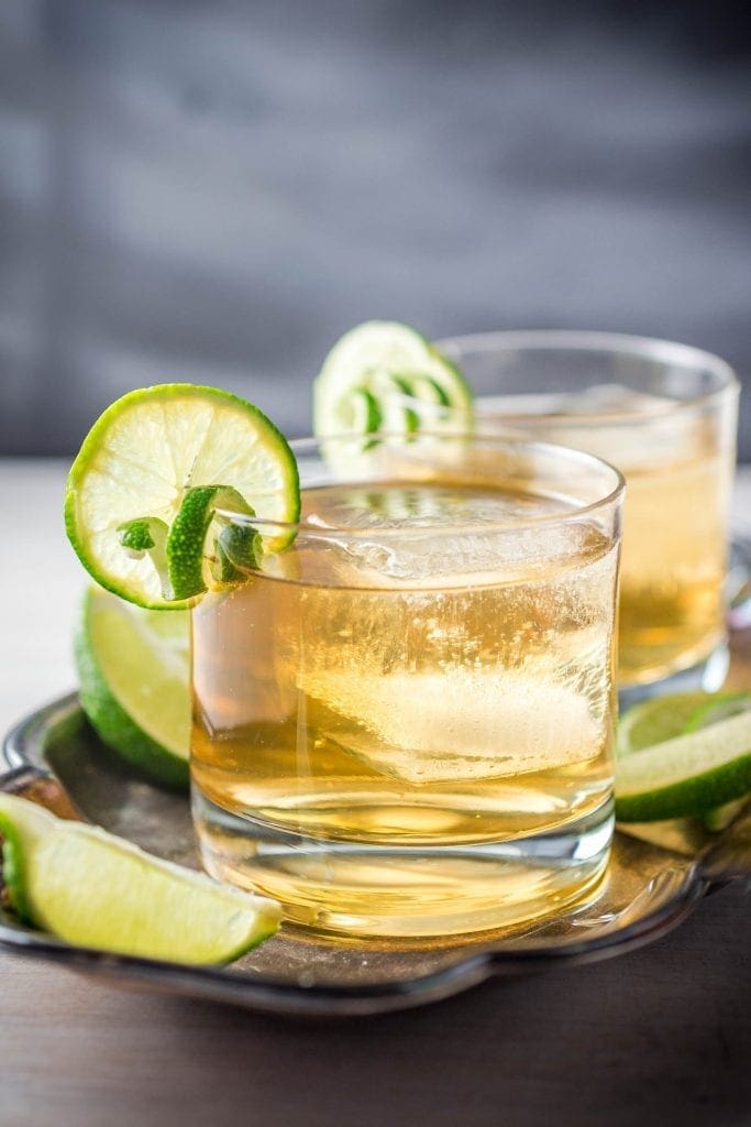 A close up of two cocktails with lime and ice
