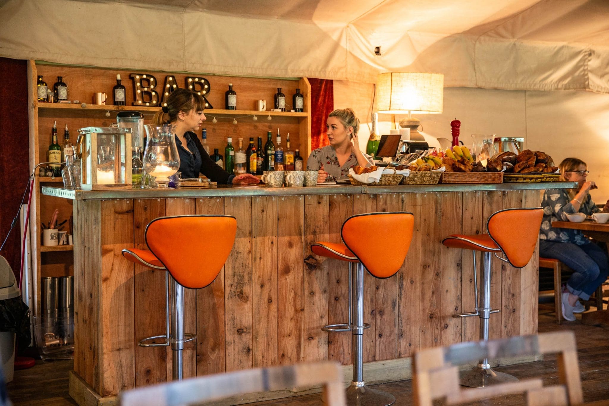 A wooden bar with orange bar stools in front of it