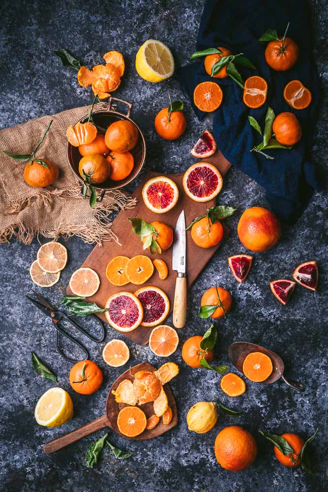 An assortment of whole and sliced blood oranges and mandarins