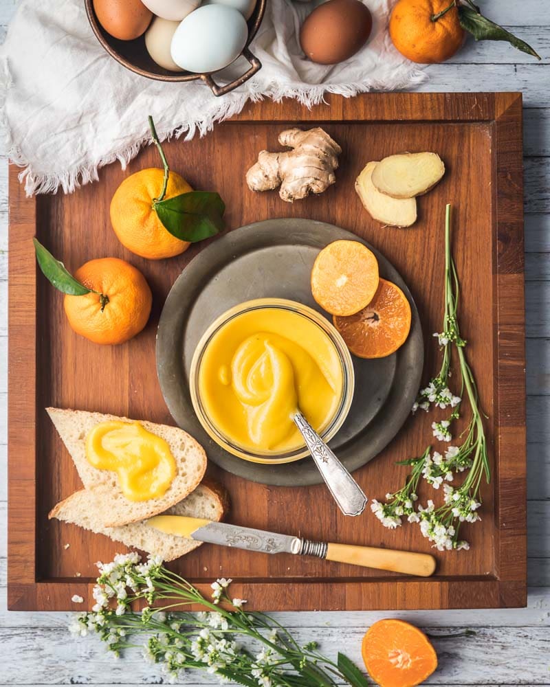 Orange curd in a jar on a tray with slices of bread slathered with it