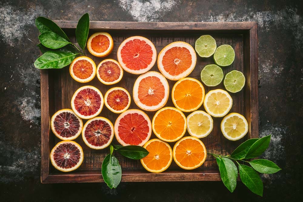 Variety of citrus fruits in wood box with leaves for homemade tonic