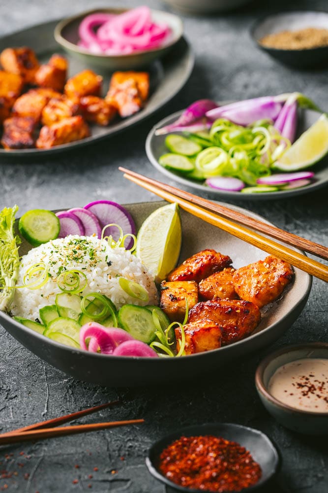 Bowls of the salmon pieces with colorful veggies and chopsticks
